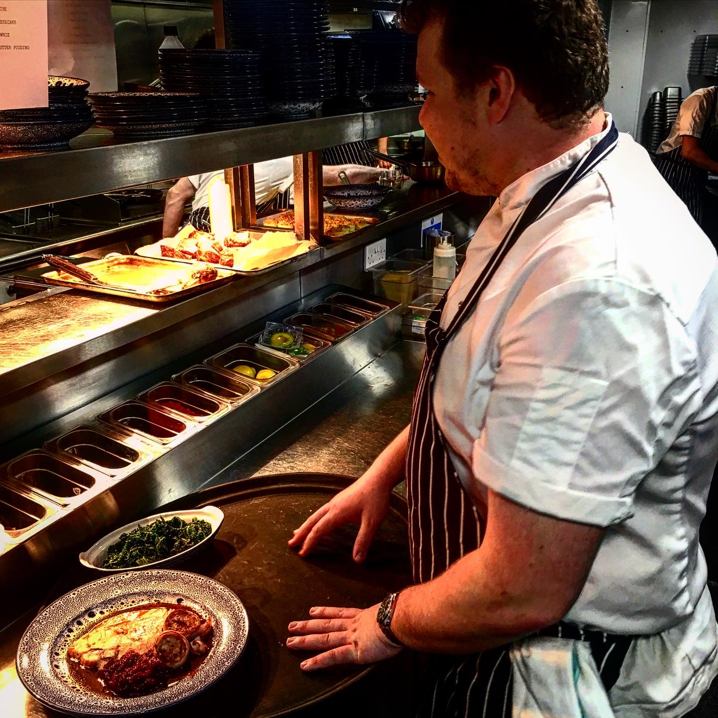 Chef checking a dish on the pass in a professional kitchen